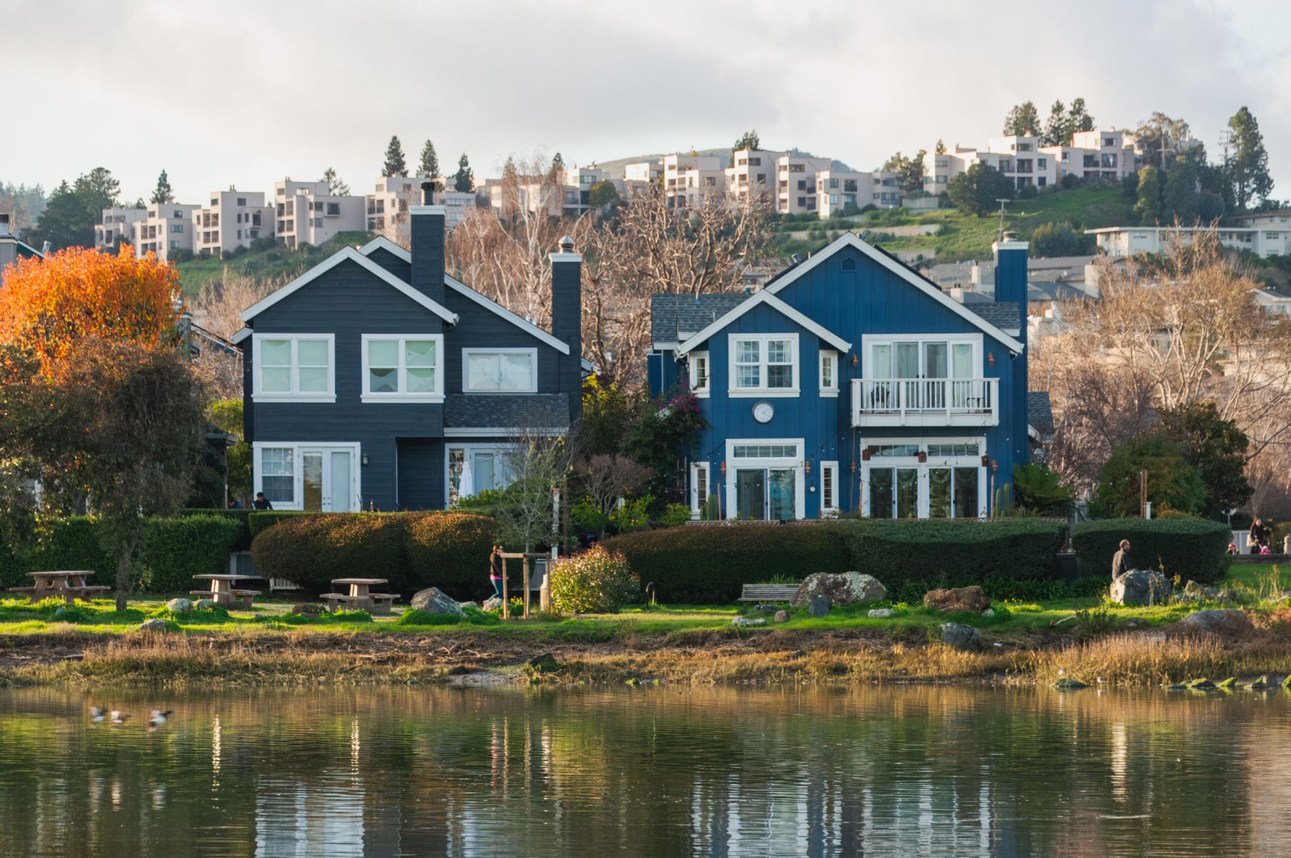 Beautiful row of waterfront homes surrounded by autumn trees reflecting in a calm river in Riverside, CA
